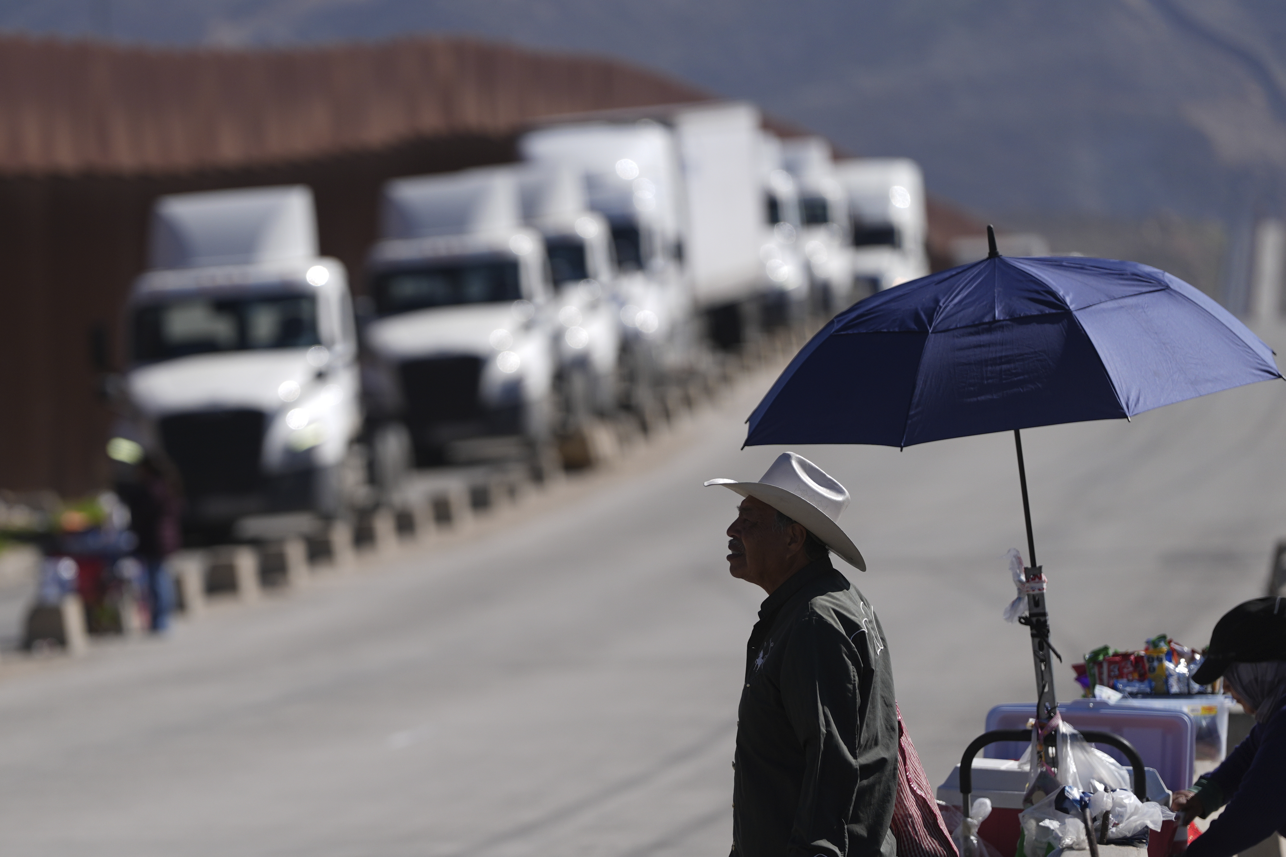 Susano Cordoba, right, sells peanuts to truck drivers lining up to cross the border into the United States as tariffs against Mexico go into effect, Tuesday, March 4, 2025, in Tijuana, Mexico. 